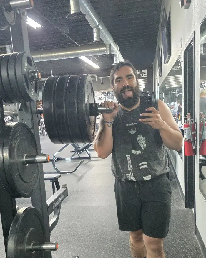 David Stubbs taking a mirror selfie in the gym, one hand on a loaded barbell